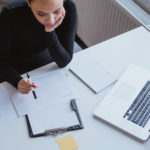 Top view of woman analyzing business growth on a chart while sitting at her desk in office.